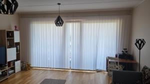 Апартамент у моря في تالين: غرفة معيشة مع نوافذ كبيرة مع ستائر بيضاء