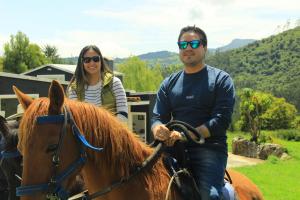 Ein Mann und eine Frau reiten ein Pferd in der Unterkunft Glamping Caliza La Calera in La Calera