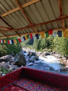 a stream with flags hanging from a roof at Last Stop Riverside wooden Huts, Camps & Dorms in Manāli
