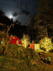a group of buildings with lights on a hill at night at Last Stop Riverside wooden Huts, Camps & Dorms in Manāli