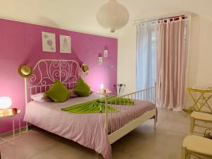 a bedroom with purple walls and a bed with green pillows at 900 Bed and Breakfast in Nola