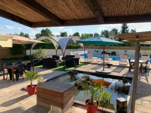 eine Terrasse mit einem Teich, Tischen und Sonnenschirmen in der Unterkunft Chambre d'hôtes NATURISTE Le Jardin Des Hirondelles in Blanzaguet-Saint-Cybard