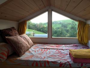 Cama en habitación con ventana grande en Tree house and shepherds hut, en Ashburton