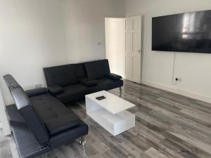 a living room with a black couch and a table at Spacious 3 bed flat near Watford Junction in Watford