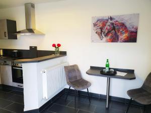 a kitchen with a counter and two chairs and a table at Moderne Ferienwohnung Black Beauty auf idyllischem Reiterhof nähe Burg Eltz in Münstermaifeld