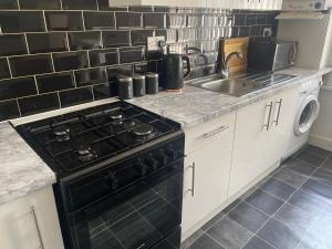 a kitchen with a black stove and a sink at Spacious 3 bed flat near Watford Junction in Watford