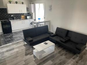 a living room with two black couches and a table at Spacious 3 bed flat near Watford Junction in Watford