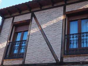 2 ventanas en un edificio de ladrillo con vallas de hierro en Casa Jacaranda, en Arenas de San Pedro