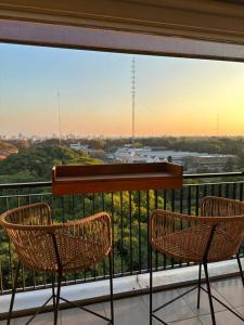 two chairs on a balcony with a view of a city at Chacarita Sunset l Andes Park in Buenos Aires