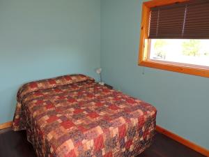 1 dormitorio con cama y ventana en Angel Rock Waterfront Cottages, en Cape Vincent