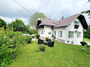 a white house with black chairs in the yard at House Ana in Plitvička Jezera