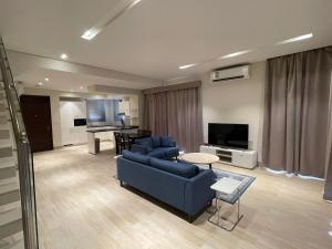 sala de estar con sofá azul y TV en Hawana Forest Island Salalah, en Ma‘mūrah