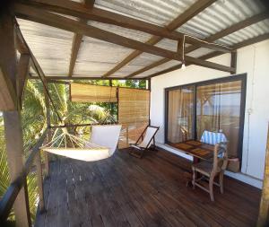 a porch with chairs and a hammock on a house at Hôtel chez Pat in Nosy Be