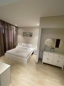 - une chambre avec un lit blanc et une télévision dans l'établissement Hawana Forest Island Salalah, à Ma‘mūrah