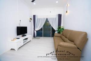 een woonkamer met een bank en een tv bij Pearl Guest House in Kerteh