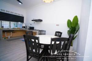 een tafel en stoelen in een kamer met een keuken bij Pearl Guest House in Kerteh