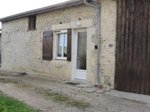 uma casa de tijolos com uma porta branca e janela em Gîte 5-6 personnes « Chez Marlène »proche de Nigloland em Meurville