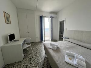 a hotel room with two beds and a desk and a computer at Hotel Castelsardo Domus Beach in Castelsardo