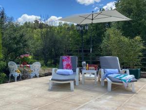 a group of chairs and an umbrella on a patio at Gorges du Verdon : Guest house avec piscine in Baudinard