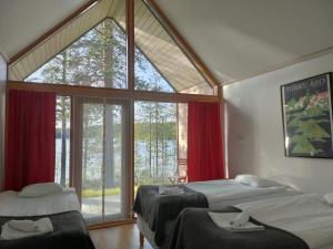 two beds in a room with a large window at Norwide - Hossan Lomakeskus in Hossa
