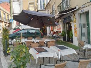 a group of tables and chairs with an umbrella at Sylhet BNB in Lisbon
