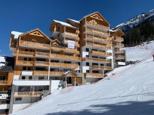 een groot gebouw bovenop een met sneeuw bedekte helling bij L'orée des pistes in Oz