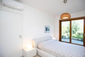 a white bedroom with a bed and a window at Villa e Appartamento Valle Incantata - Goelba in Capoliveri