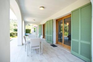 a patio with green shutters and a table and chairs at Villa e Appartamento Valle Incantata - Goelba in Capoliveri