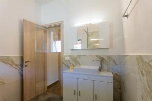 a white bathroom with a sink and a mirror at Kampos Kassiopi Apartment in Kassiopi