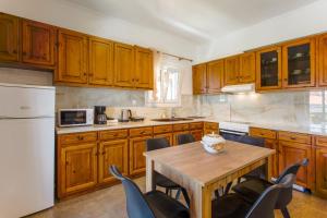a kitchen with wooden cabinets and a table with chairs at Kampos Kassiopi Apartment in Kassiopi