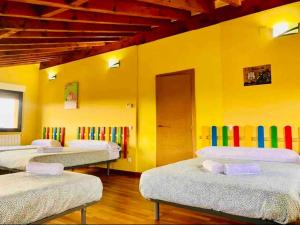 3 camas en una habitación con una pared amarilla en Villa Arboleda, en La Losa