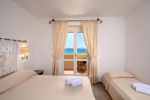 two beds in a room with a view of the ocean at Hotel Castello in Golfo Aranci