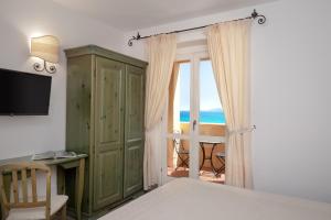 una camera da letto con armadio verde e porta scorrevole in vetro di Hotel Castello a Golfo Aranci