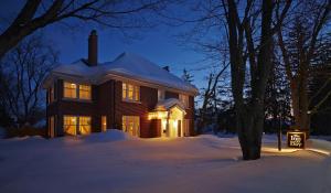 a house with lights on in the snow at night at The Inn on Bay in Gravenhurst