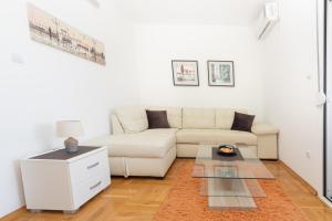 a white living room with a white couch and a table at Apartments Horizont in Budva
