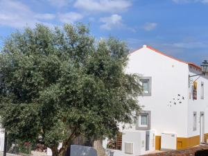 Una casa blanca con un árbol delante. en adubai Obidos, en Óbidos