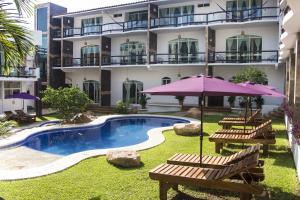 un hotel con piscina con panchine e ombrellone di Hotel Rockaway a Puerto Escondido