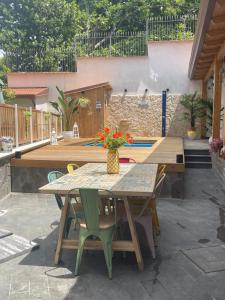 einen Holztisch mit Stühlen und eine Vase aus Blumen auf einer Terrasse in der Unterkunft Villa LORY in Castellammare di Stabia