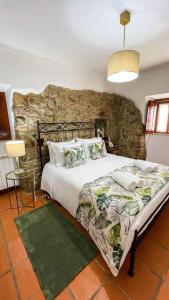 1 dormitorio con cama y pared de piedra en Sitio Terra do Loureiro, en Porto de Mós