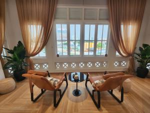 a living room with chairs and a table and a window at hovoh homes Bugis Rochor in Singapore