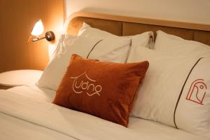 uma cama com almofadas brancas e uma almofada com a palavra uo em Tuong Boutique Resort Mui ne em Mui Ne