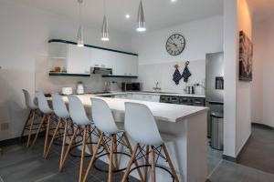 Una cocina con gabinetes blancos y una encimera con taburetes. en Modern & Tranquil Mitai House, en Brenton-on-Sea
