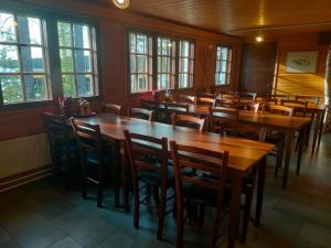 a restaurant with wooden tables and chairs and windows at Norwide - Hossan Lomakeskus in Hossa