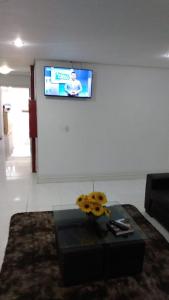 a living room with a table and a tv on a wall at HOTEL ECONOMICO - 150m Santa Casa, Prox Assembleia e UFRGS in Porto Alegre