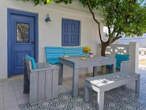 a patio with a table and chairs and a blue door at Thea Menetes in Karpathos Town