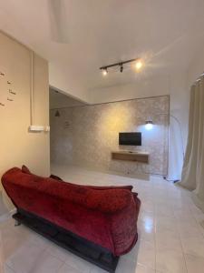 uma sala de estar com um sofá vermelho e uma televisão em Cozy Apartment - Sri Lagenda Resort Langkawi em Kuah