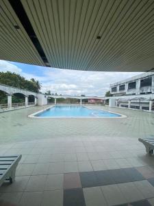 uma grande piscina num edifício com dois bancos em Cozy Apartment - Sri Lagenda Resort Langkawi em Kuah