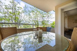 einen Glastisch mit Stühlen auf dem Balkon in der Unterkunft Seafront Maris by EL-PI TOURS in Dobrinj
