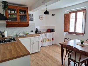 eine Küche mit weißen Schränken und einem Holztisch in der Unterkunft Casa Vacanze La Barca in Fiattone