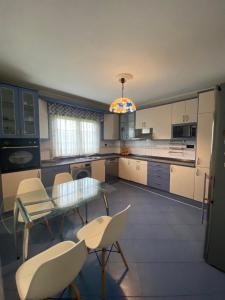 a kitchen with a glass table and white chairs at Chalet en Suances in Ongayo